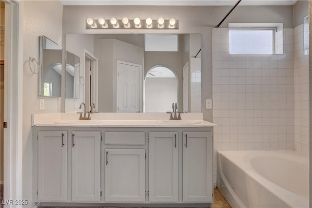 bathroom featuring washtub / shower combination, double vanity, and a sink