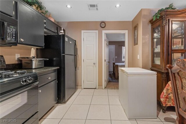 kitchen featuring visible vents, black appliances, light tile patterned floors, and dark cabinets