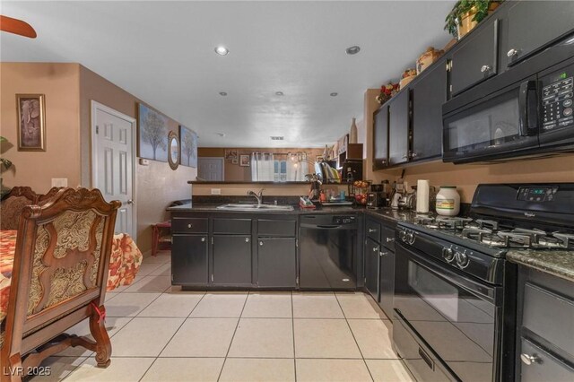 kitchen with a peninsula, a sink, black appliances, and dark countertops