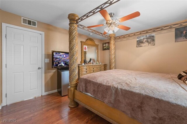 bedroom with ceiling fan, visible vents, baseboards, and wood finished floors