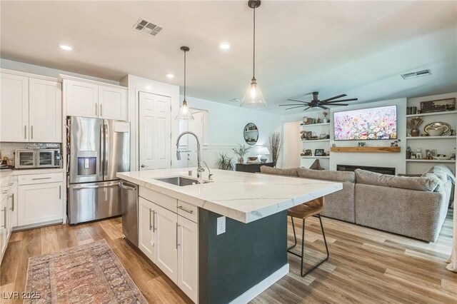 12356 Notch Trail Ave, Las Vegas, NV 89138 - kitchen with stainless steel appliances, a sink, white cabinets, decorative light fixtures, and recessed lighting