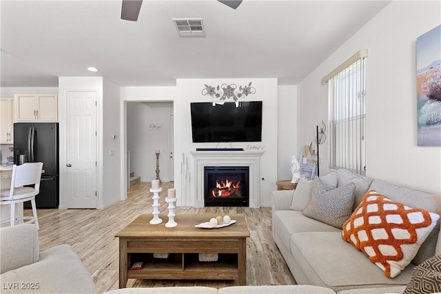 10052 Silver Comet Ct, Las Vegas, NV 89178 - living room with light wood-type flooring, ceiling fan, a glass covered fireplace, and recessed lighting