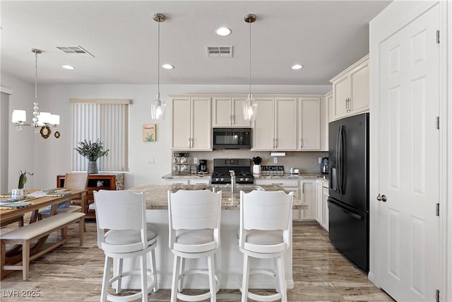 10052 Silver Comet Ct, Las Vegas, NV 89178 - kitchen with black appliances, light stone counters, decorative backsplash, a kitchen island with sink, and pendant lighting