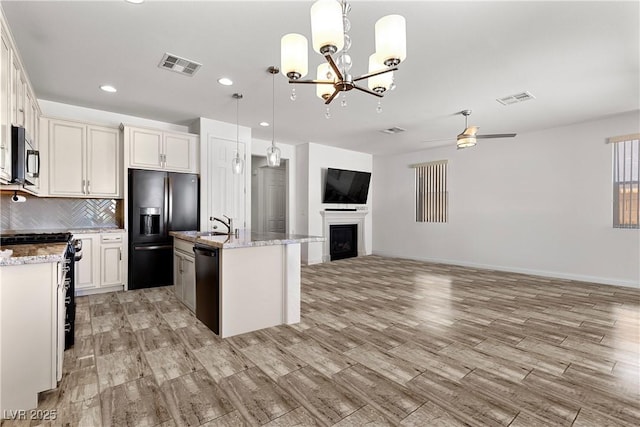 10052 Silver Comet Ct, Las Vegas, NV 89178 - kitchen with black appliances, open floor plan, light wood-style floors, decorative backsplash, and a fireplace
