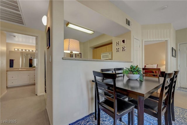 carpeted dining space with baseboards and visible vents