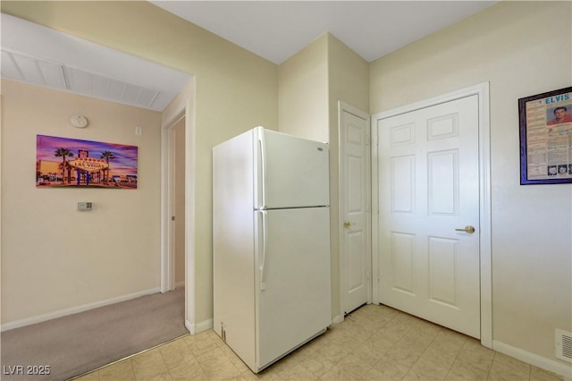 kitchen featuring visible vents, baseboards, freestanding refrigerator, and light floors