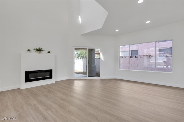 6509 Old Oxford Ave, Las Vegas, NV 89108 - unfurnished living room featuring light wood-style floors, baseboards, recessed lighting, and a glass covered fireplace