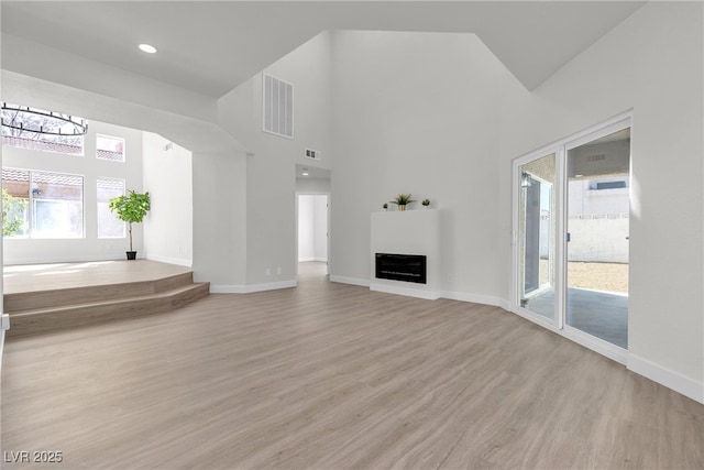 6509 Old Oxford Ave, Las Vegas, NV 89108 - unfurnished living room with baseboards, light wood-type flooring, a towering ceiling, and visible vents