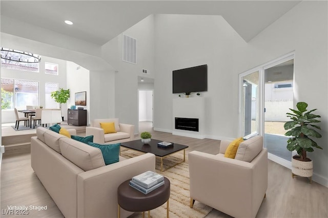 6509 Old Oxford Ave, Las Vegas, NV 89108 - living area with a fireplace, light wood finished floors, visible vents, and a towering ceiling