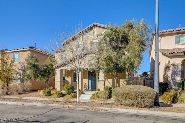 view of front of house featuring a tiled roof, stucco siding, and fence