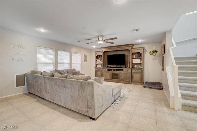 living area featuring visible vents, baseboards, light tile patterned floors, a ceiling fan, and stairs