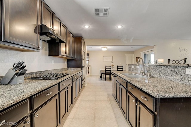 kitchen with dark brown cabinetry, gas stovetop, visible vents, under cabinet range hood, and a sink