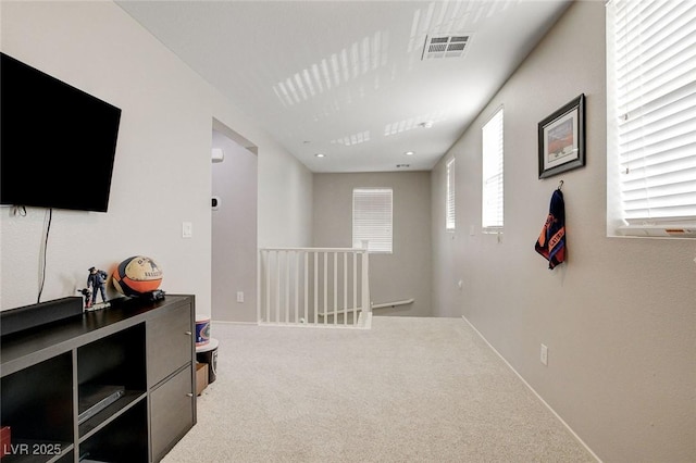hall featuring an upstairs landing, visible vents, baseboards, and carpet
