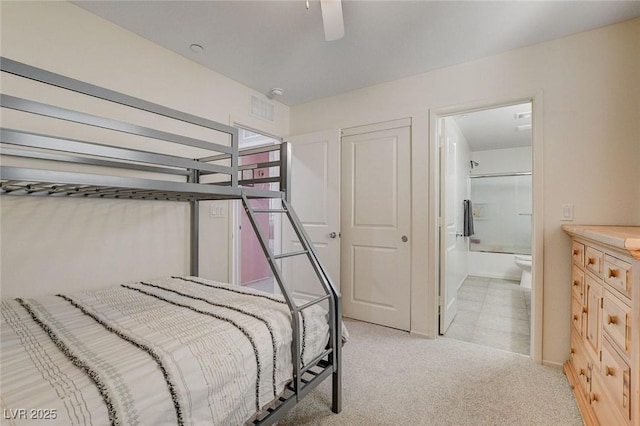 bedroom with visible vents, light colored carpet, and connected bathroom