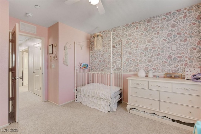 bedroom featuring visible vents, baseboards, ceiling fan, wallpapered walls, and light carpet