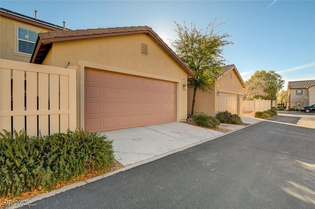 multi unit property featuring a garage, stucco siding, and fence