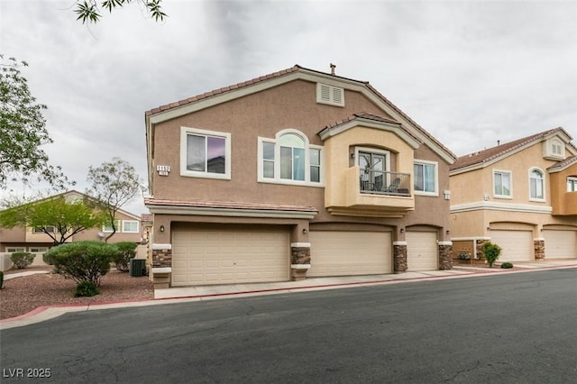 view of front of home with a balcony, stucco siding, stone siding, and an attached garage