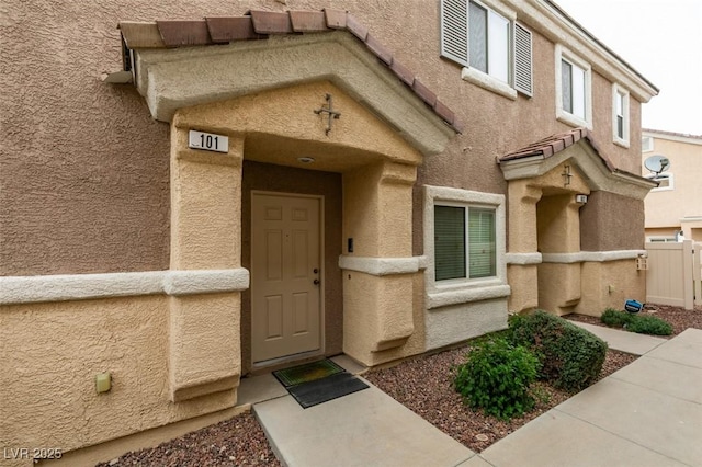 property entrance featuring stucco siding and fence