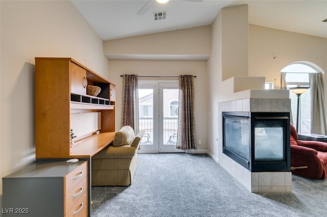 office area featuring ceiling fan, vaulted ceiling, visible vents, carpet floors, and a tile fireplace