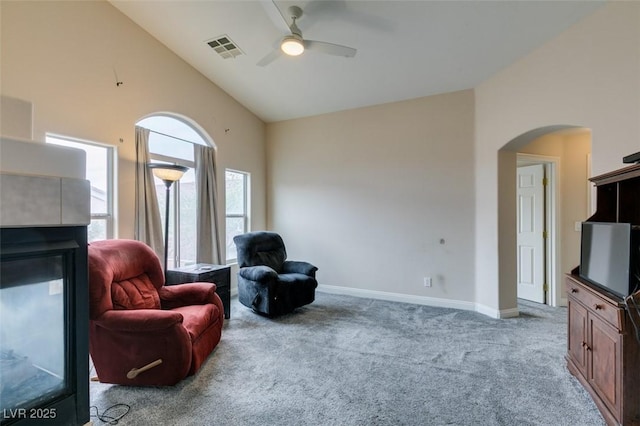 living area featuring visible vents, arched walkways, ceiling fan, high vaulted ceiling, and carpet flooring