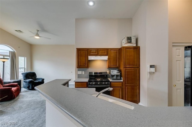 kitchen featuring gas range oven, under cabinet range hood, visible vents, ceiling fan, and a sink