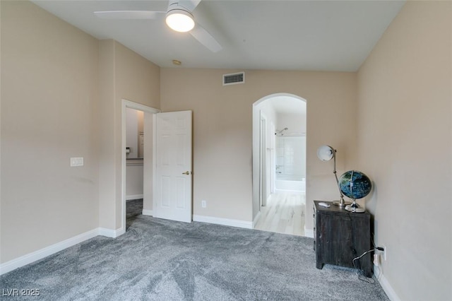 unfurnished bedroom featuring arched walkways, carpet flooring, baseboards, and visible vents