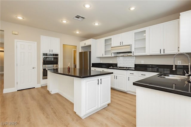 kitchen featuring range hood, visible vents, a sink, light wood-style floors, and stainless steel appliances