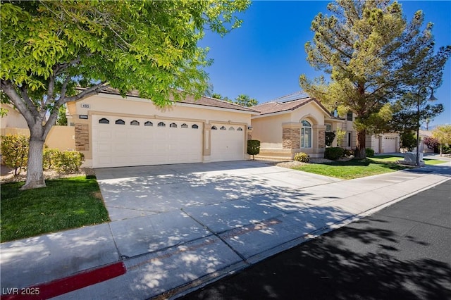 mediterranean / spanish house featuring concrete driveway, an attached garage, stone siding, and stucco siding