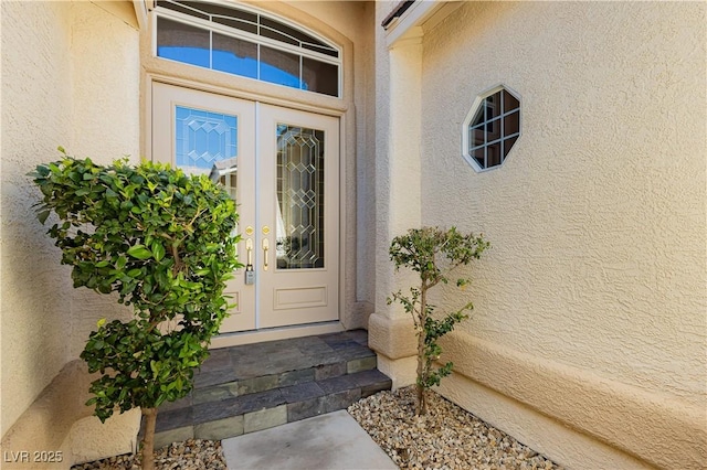 entrance to property featuring french doors and stucco siding
