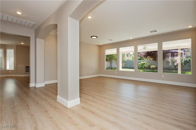 unfurnished living room with baseboards, recessed lighting, light wood-style flooring, visible vents, and arched walkways