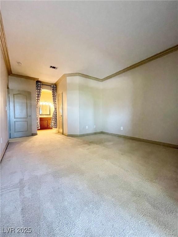 spare room featuring crown molding, baseboards, and carpet flooring