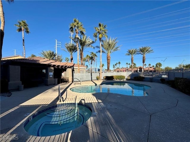 view of swimming pool with a patio area, fence, and an in-ground hot tub
