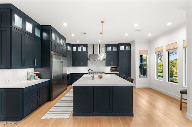 kitchen featuring stainless steel built in fridge, wall chimney range hood, tasteful backsplash, baseboards, and light countertops