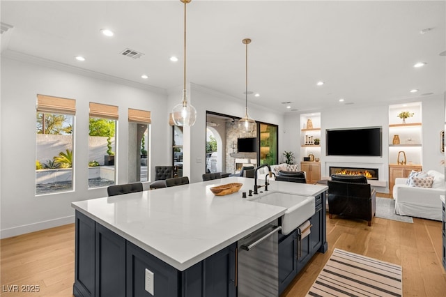 kitchen featuring a lit fireplace, a sink, light wood-type flooring, recessed lighting, and open floor plan