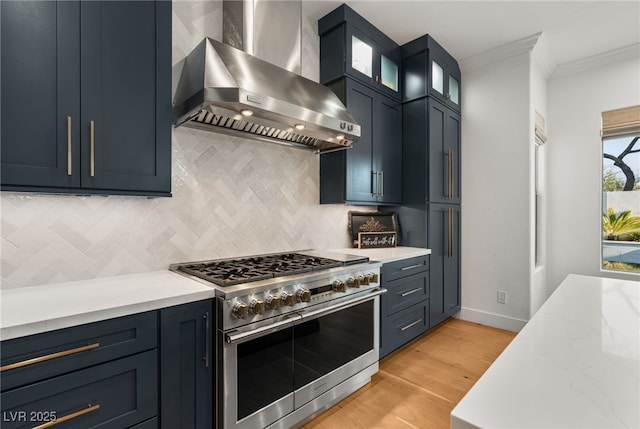 kitchen featuring double oven range, wall chimney range hood, ornamental molding, decorative backsplash, and light wood-style flooring