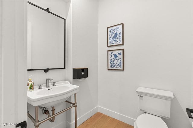 bathroom with toilet, wood finished floors, and baseboards