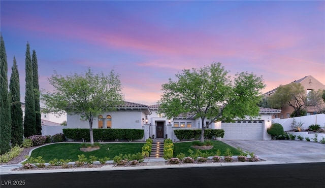 mediterranean / spanish-style house featuring driveway, an attached garage, stucco siding, and a tiled roof