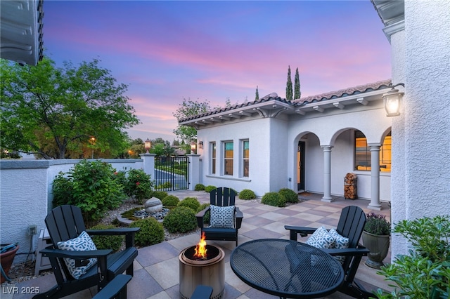 patio terrace at dusk with an outdoor fire pit and fence
