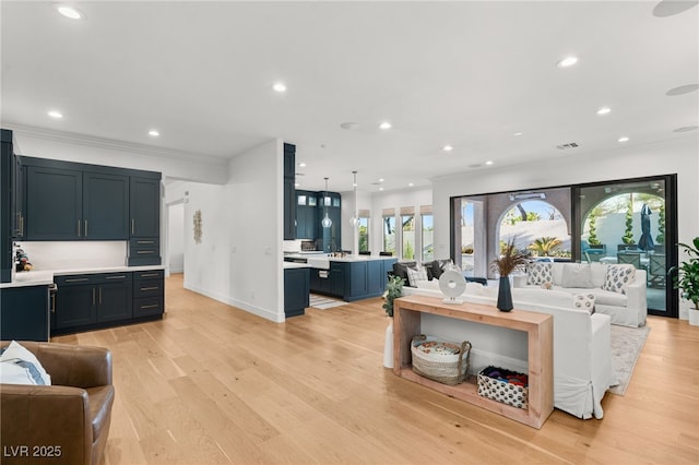 living room with recessed lighting, light wood-type flooring, baseboards, and crown molding