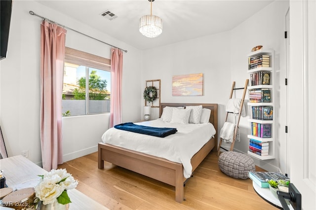 bedroom featuring wood finished floors, a chandelier, and baseboards
