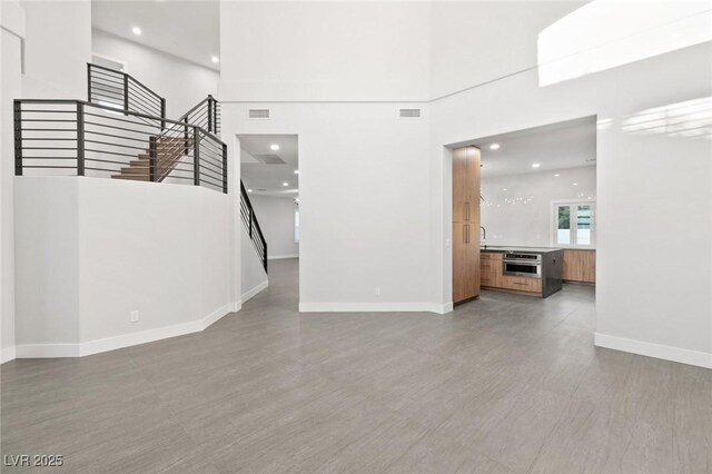 2236 Timber Rose Dr, Las Vegas, NV 89134 - unfurnished living room featuring baseboards, recessed lighting, a high ceiling, stairs, and visible vents