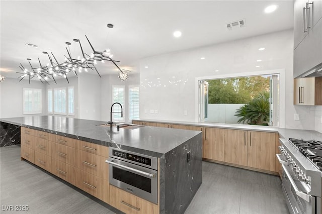 2236 Timber Rose Dr, Las Vegas, NV 89134 - kitchen featuring visible vents, modern cabinets, stainless steel appliances, a large island with sink, and a sink