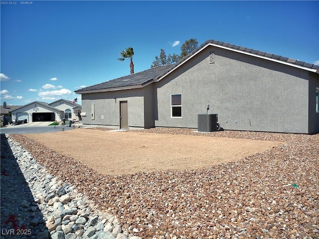 rear view of house featuring stucco siding and cooling unit