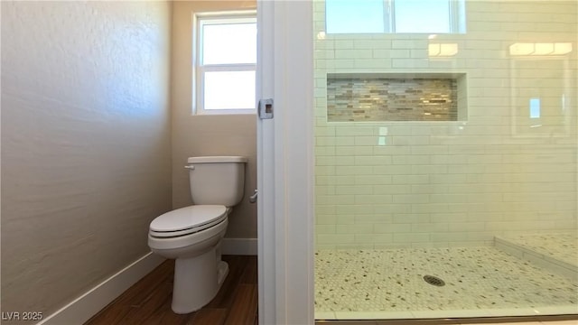 bathroom with baseboards, a shower stall, toilet, and wood finished floors