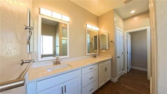 full bathroom featuring double vanity, recessed lighting, a sink, and wood finished floors