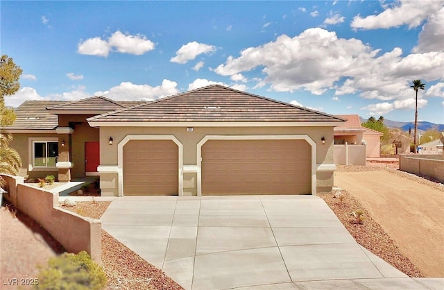 view of front of property with driveway, fence, a mountain view, an attached garage, and stucco siding