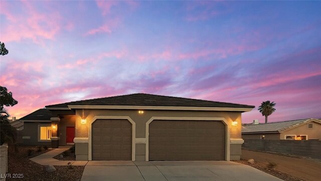ranch-style home featuring concrete driveway, stucco siding, and a garage