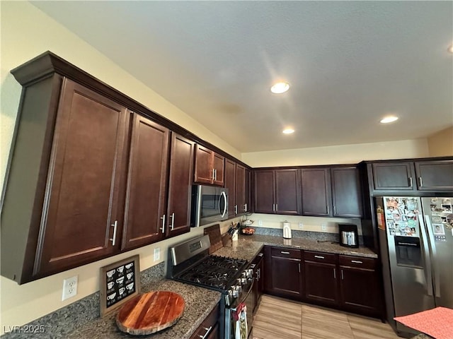 kitchen with stainless steel appliances, recessed lighting, dark brown cabinetry, and dark stone countertops