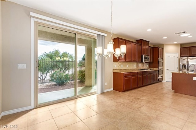 kitchen featuring hanging light fixtures, a notable chandelier, appliances with stainless steel finishes, light stone countertops, and decorative backsplash