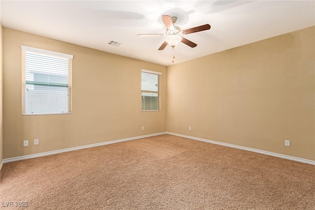 carpeted empty room with visible vents, baseboards, and a ceiling fan